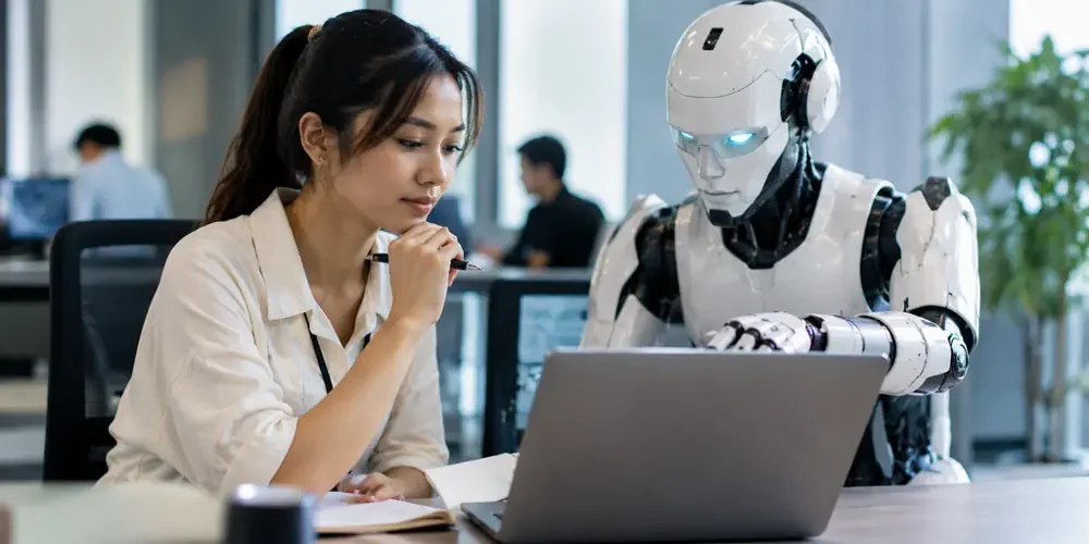 Woman and humanoid robot work together on a laptop